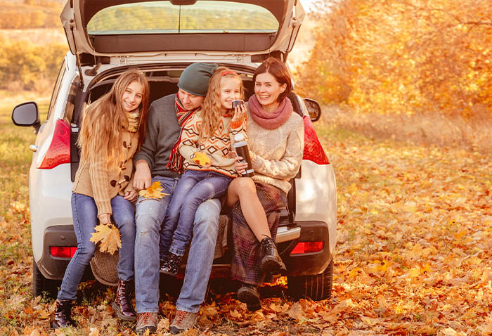 Family sitting in the open trunk of a car surrounded by autumn leaves. Family sitting in the open trunk of a car surrounded by autumn leaves.