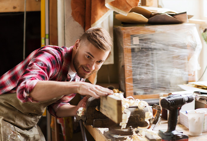 Woodworker shaping a piece of wood with a hand plane at a workshop bench. Woodworker shaping a piece of wood with a hand plane at a workshop bench.